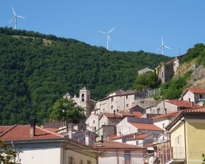 Turbine eoliche sopra la collina di un borgo